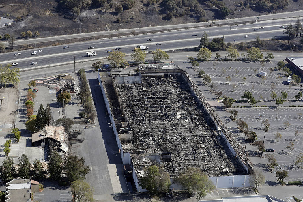 A large commercial building ravaged by a wildfire is seen along highway 101, top, Saturday, Oct. 14, 2017, in Santa Rosa, Calif. (AP Photo/Marcio Jose Sanchez)