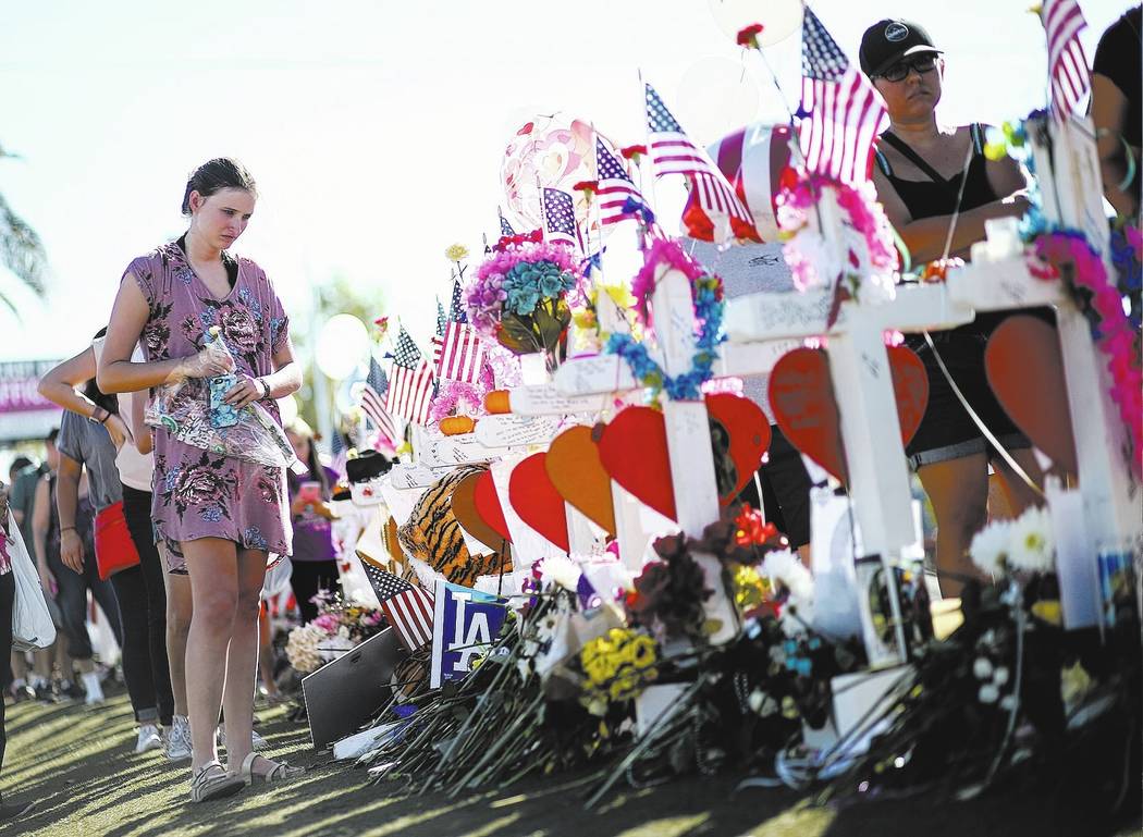 Kylie Wright of Flagstaff, Ariz. leaves behind roses at a makeshift memorial for victims of Sunday's mass shooting near the &quot;Welcome to Fabulous Las Vegas&quot; sign in Las Vegas on S ...