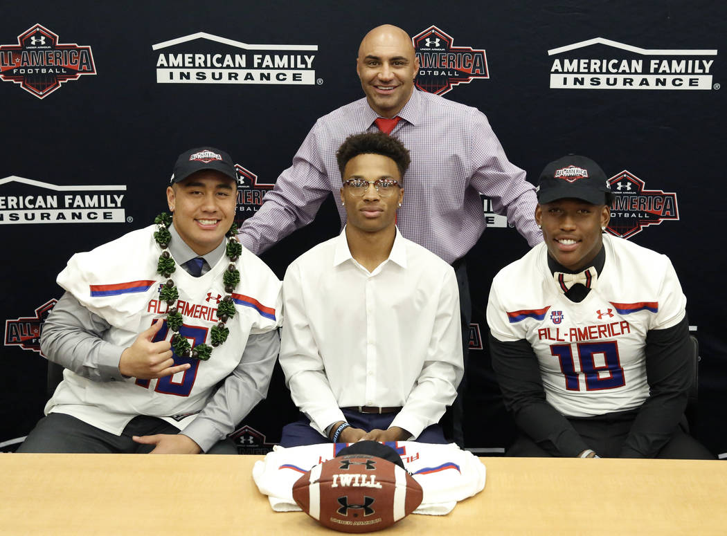 Bishop Gorman's head coach Kenny Sanchez, standing, with offensive guard Jacob Isaia, left, quarterback Dorian Thompson-Robinson and tight end Brevin Jordan, right, after his players received thei ...