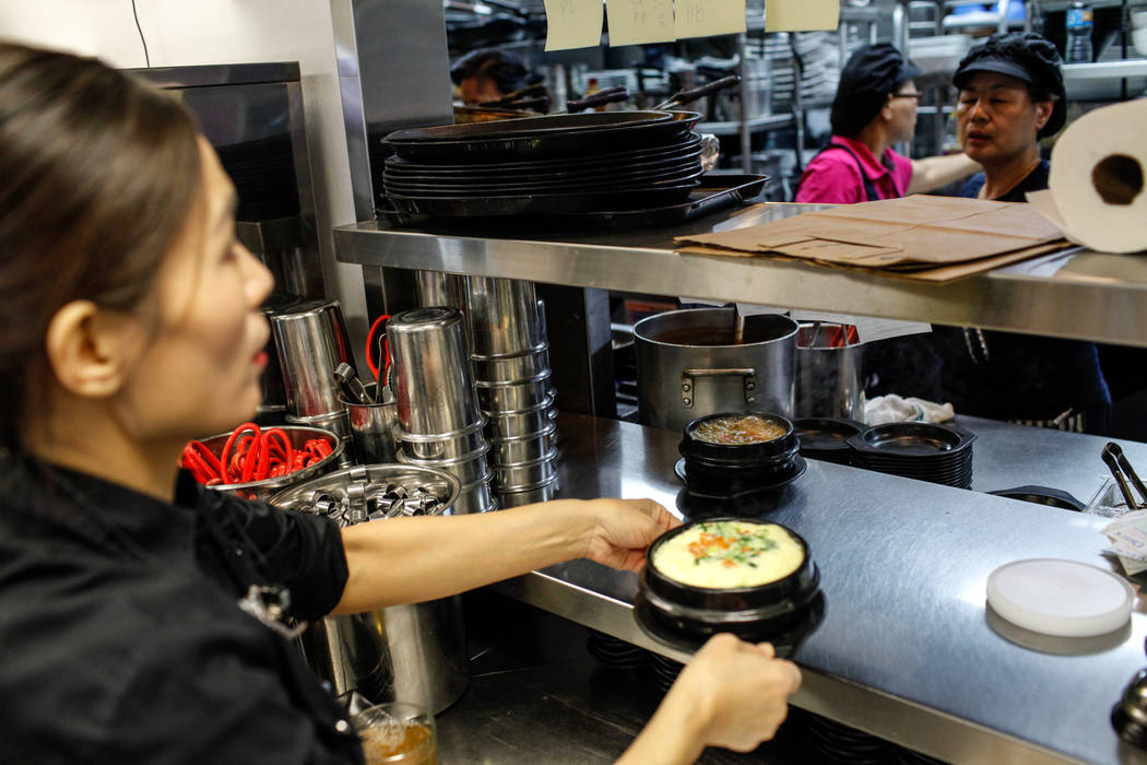 Grace Kim, 48, of Las Vegas, left, grabs food prepared in the kitchen before serving it to customers at Lee's Korean BBQ in Las Vegas, Tuesday, Oct. 24, 2017. Owner Hae Un Lee attended a meeting T ...