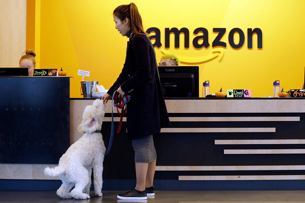 In this Wednesday, Oct. 11, 2017, photo, an Amazon employee gives her dog a biscuit as the pair head into a company building, where dogs are welcome, in Seattle. (AP Photo/Elaine Thompson)