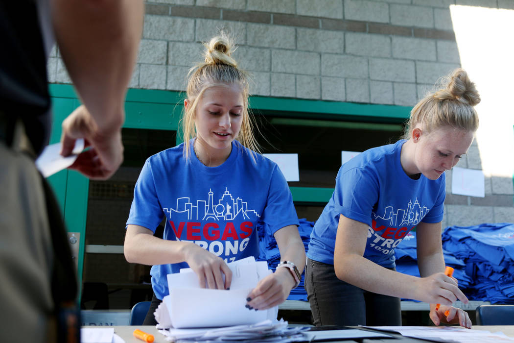 Seniors Cozette Van Wei, left, and Maddie Jensen, 17, help the principal of Johnston Middle School pick up an order  of Las Vegas Strong T-shirts at Green Valley High School in Las Vegas, Wednesda ...