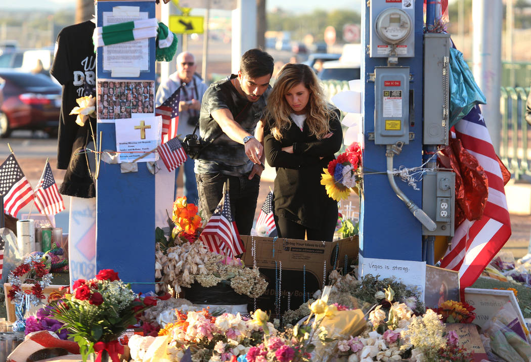 Francesco Floris, left, and Irene Corzo, both of Italy, visit a memorial at the Welcome to Fabulous Las Vegas sign in Las Vegas, Tuesday, Oct. 17, 2017, honoring the victims of the 91 Harvest mass ...