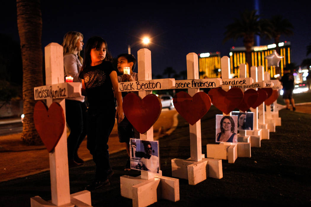 Jessica Reyes of Las Vegas, 7, holds a candle as she walks past crosses honoring the victims of Sunday night's shooting during a vigil at the Welcome to Fabulous Las Vegas sign in Las Vegas, Thurs ...