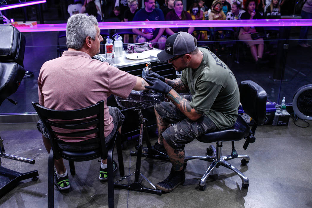Kostantinos Kitsopoulos, originally from Athens and now living in Las Vegas, 48, left, gets tattooed by Jason &quot;Kapps&quot; Capps, of Las Vegas, 35, right, during a fundraising event f ...