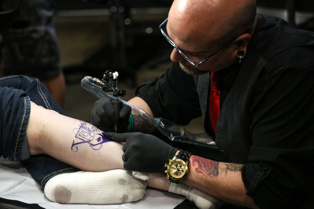 Jill Flynn, 52, left, gets tattooed by Walter &quot;Sausage&quot; Frank, 47, right, both of Las Vegas, during a fundraising event for the victims of the Route 91 Harvest Festival shooting  ...