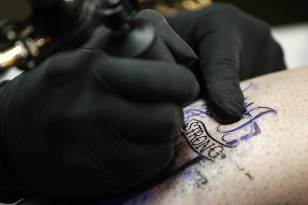 Walter "Sausage" Frank, 47, left, tattoos Jill Flynn, 52, right, both of Las Vegas, during a fundraising event for the victims of the Route 91 Harvest Festival shooting at Revolt ...