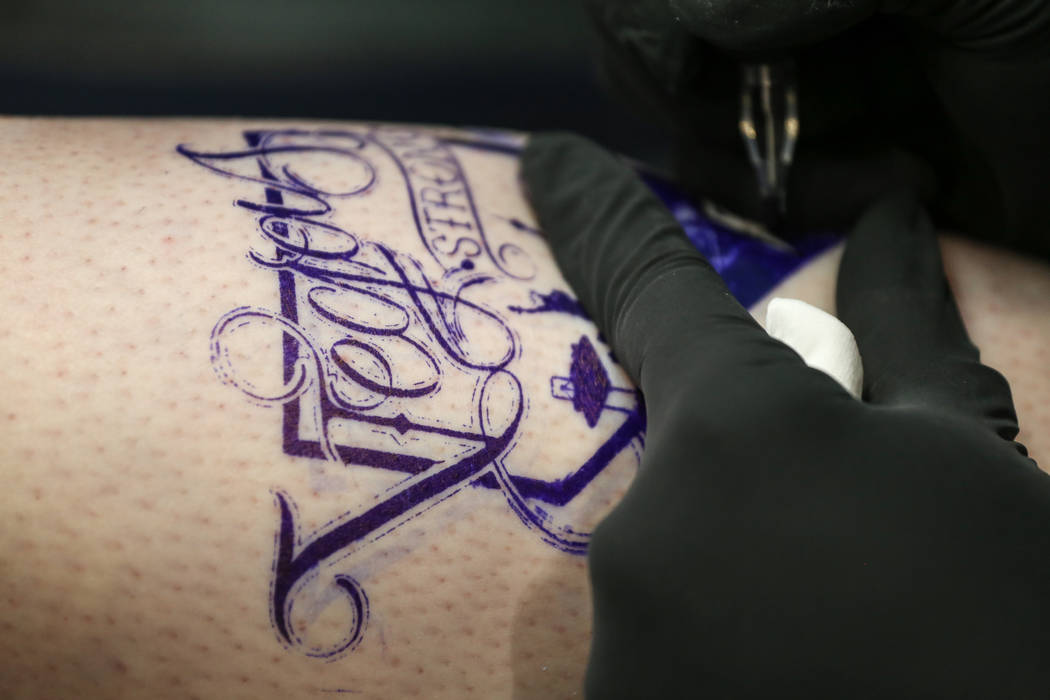 Jill Flynn, 52, left, gets tattooed by Walter "Sausage" Frank, 47, right, both of Las Vegas, during a fundraising event for the victims of the Route 91 Harvest Festival shooting ...