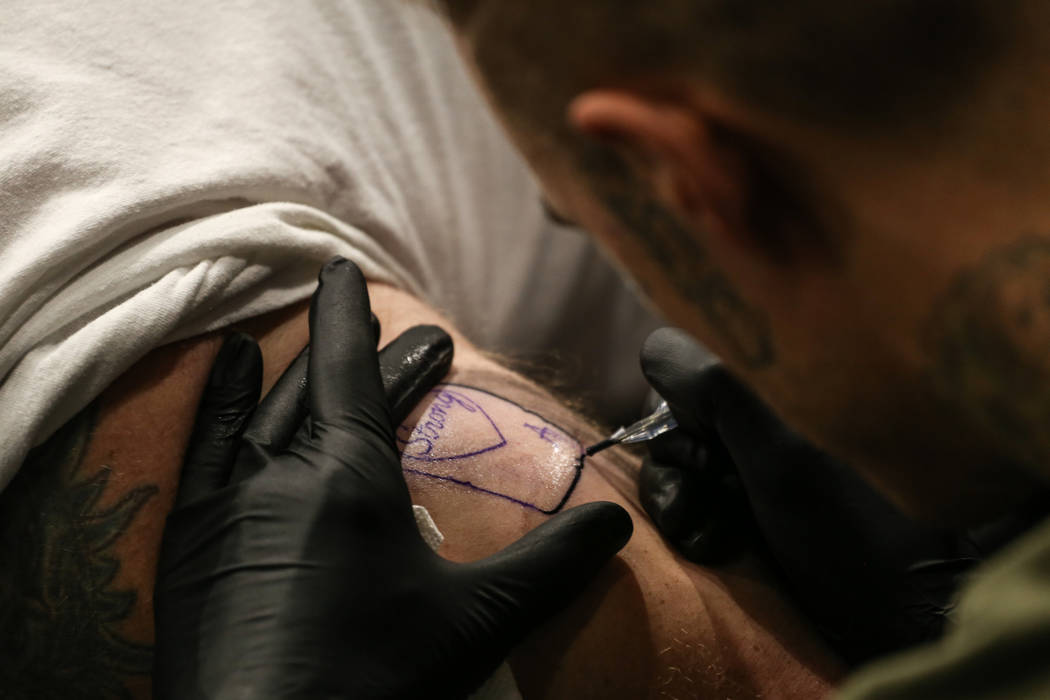 Rhett Harris, 37, left, gets tattooed by Chad Lambert, 34, right, both of Las Vegas, during a fundraising event for the victims of the Route 91 Harvest Festival shooting at Revolt Tattoos in Las V ...