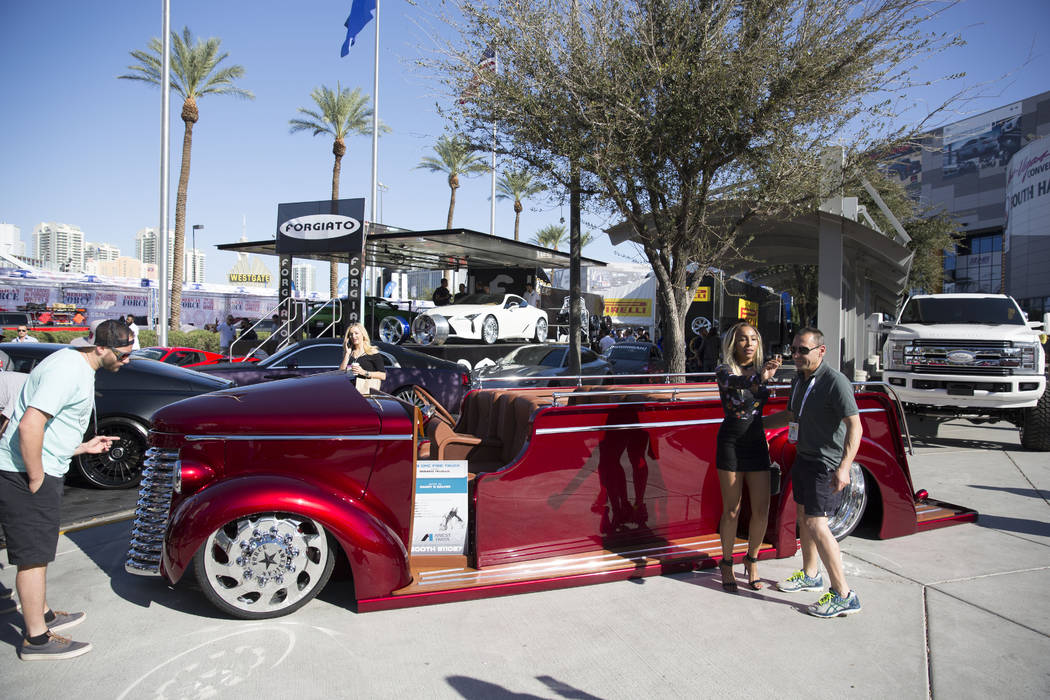 Attendees of the Specialty Equipment Market Association (SEMA) show pose in front of the unique vehicles on display at the Las Vegas Convention Center Tuesday, Oct. 31, 2017, as part of the four-d ...