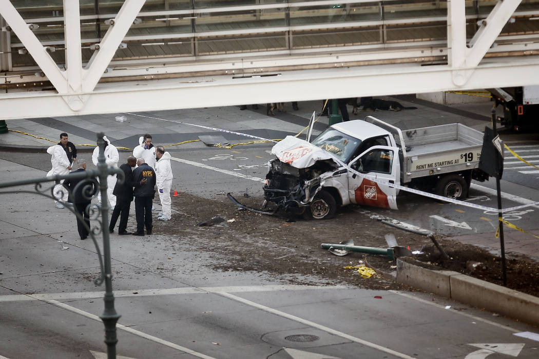 Authorities stand near a damaged Home Depot truck after a motorist drove onto a bike path near the World Trade Center memorial, striking and killing several people Tuesday, Oct. 31, 2017, in New Y ...
