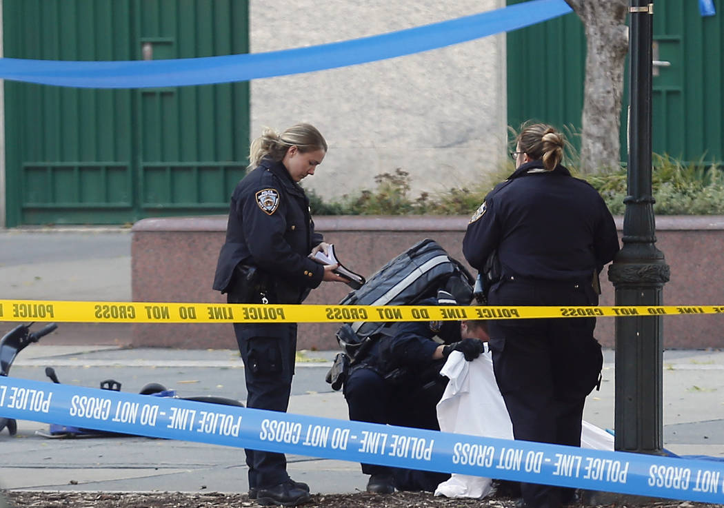 A paramedic looks at a body covered under a white sheet along a bike path, Tuesday Oct. 31, 2017, in New York. (Bebeto Matthews/AP)