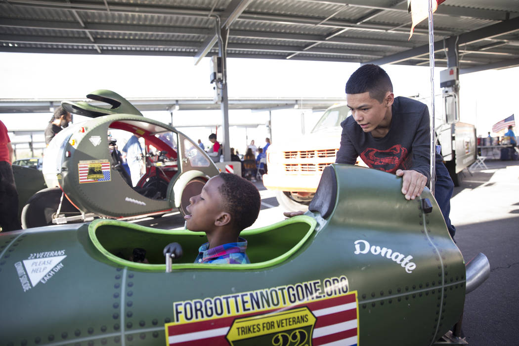 Terrell Moseley Jr., left, 10, with the help of Dawnavon Carreon, 15, rides a trike during the 3rd Annual Car Show and BBQ in celebration of Veterans Day at the VA Southern Nevada Healthcare Syste ...
