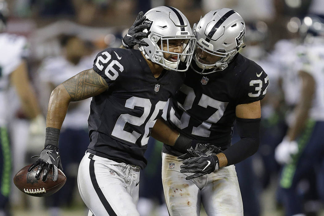 Oakland Raiders safety Shalom Luani (26) is congratulated by Anthony Cioffi (37) after intercepting a pass against the Seattle Seahawks during the first half of an NFL preseason football game in O ...