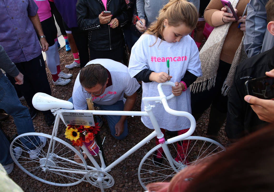 Addi Thompson, 9, writes a message on the ghost bike of Cara Cox during a ghost bike memorial ceremony on Saturday, Nov. 4, 2017, in Henderson. Cox was struck by vehicle while riding her bike on O ...