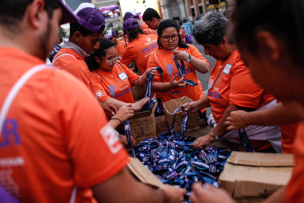 Charlene Gamayo, 16, of Las Vegas, third from right, assembles medals for runners in the Rock 'n' Roll Las Vegas Marathon along the Strip near The Mirage in Las Vegas, Sunday, Nov. 12, 2017. Joel  ...