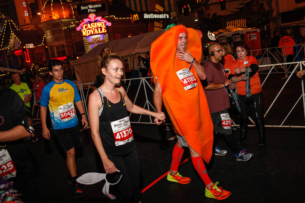 Jodi Jacobs, left, and Nathaniel Jacobs, right, both of Las Vegas cross the finish line at the 10K run of the Rock 'n' Roll Las Vegas Marathon along the Strip near The Mirage in Las Vegas, Sunday, ...