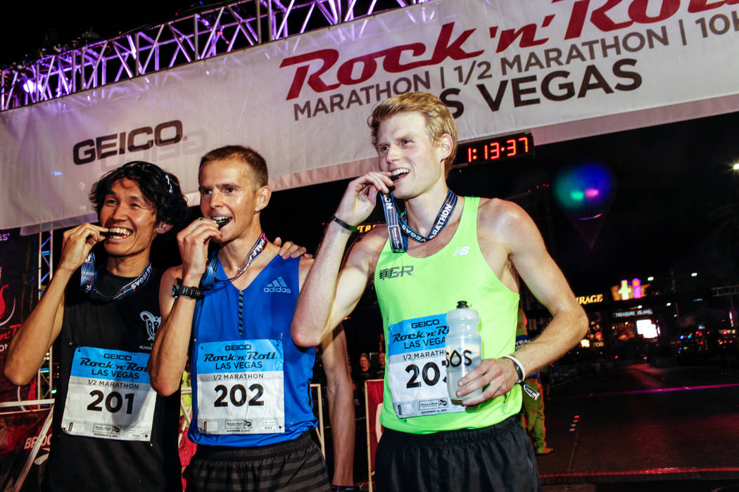 Second place winner Yuki Yagi of Japan, left, first place winner Jeffrey Eggleston of Boulder, center, and third place winner Wilkerson Given of the Woodlands, right, bite their medals after cross ...