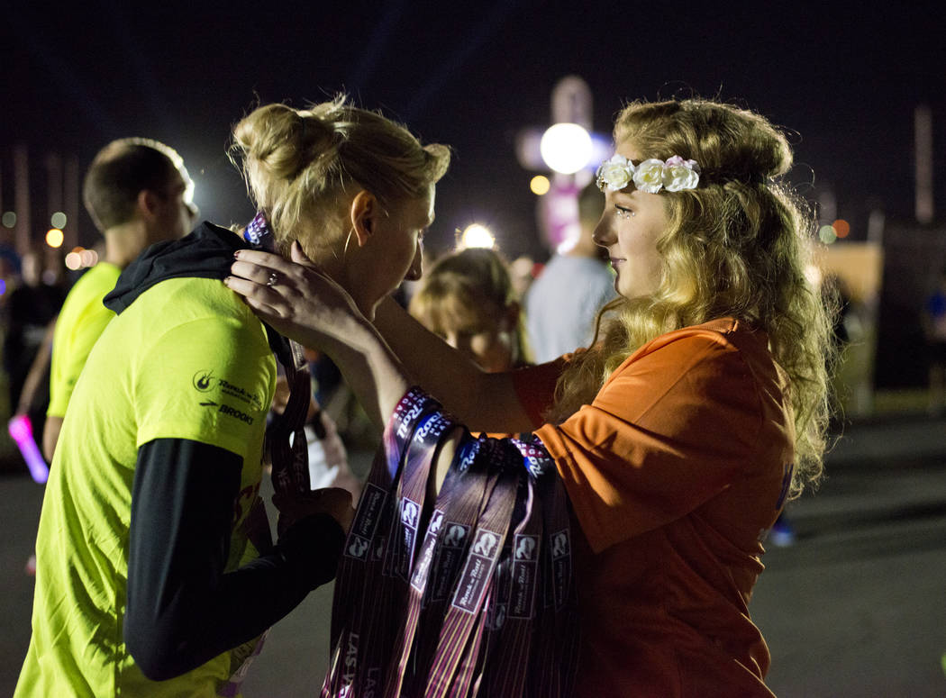 Event volunteer Arita McCabe, right, puts a medal around the neck of Jennifer Watson after the 5K portion of the Rock ԮՠRoll Las Vegas Marathon at the Las Vegas Festival Grounds on The ...