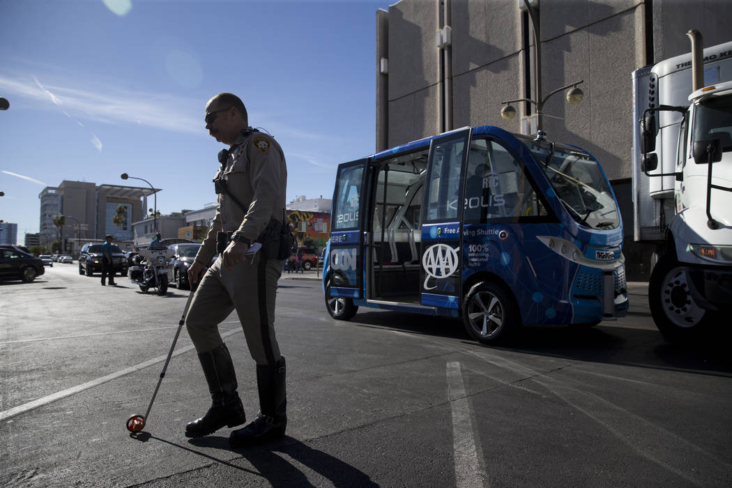 A Las Vegas police officer at the scene of an accident between a truck and a driverless electric shuttle near Fremont Street and S. 6th Street in Las Vegas during the launch day of the autonomous  ...