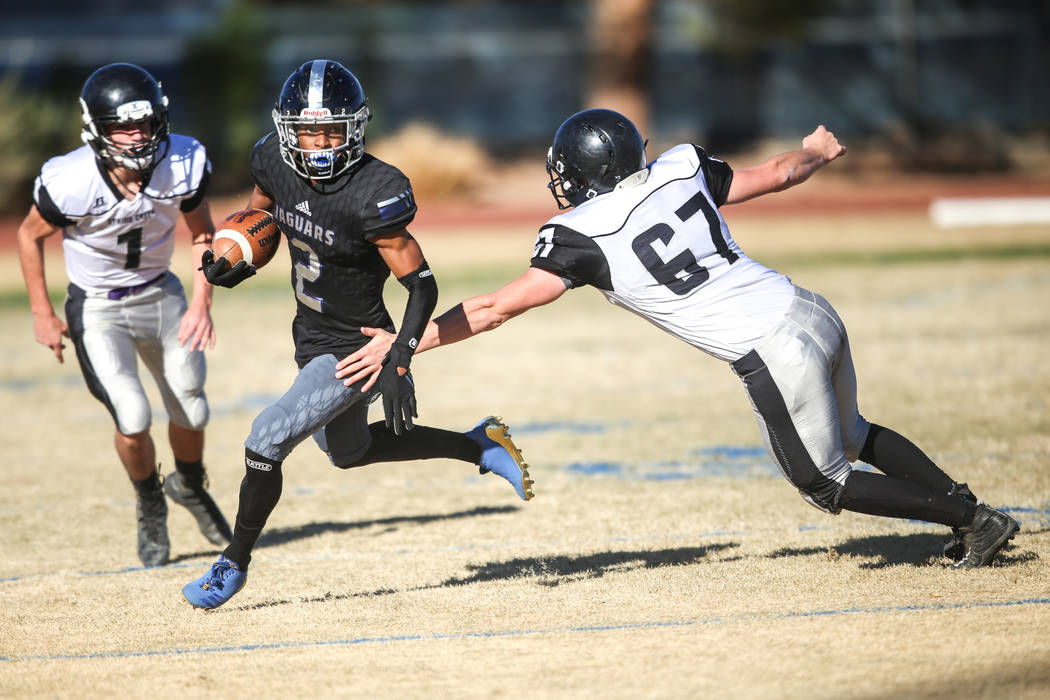 Desert Pines' Tye Moore (2), center, runs the ball past Spring Creek's Andrew Armstrong (67), right, during the second quarter of the Class 3A State football game at Desert Pines High School in La ...