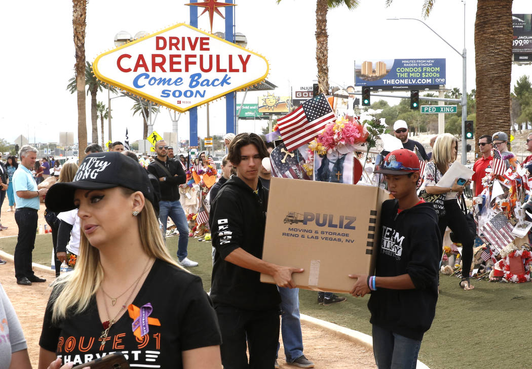 Matthew Ferandell, center, cousin of Angela Gomez, Oct. 1 shooting victim, and Ben Riccardi, right, carry boxed up cross and items from the Route 91 Harvest memorial at the Welcome to Fabulous Las ...