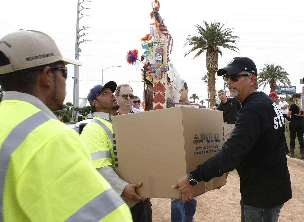 Chris Davis, right, helps Clark County employees carrying his Las Vegas shooting victim daughter Neysa Tonks' cross and items at the Welcome to Fabulous Las Vegas sign Sunday, Nov. 12, 2017. Fifty ...