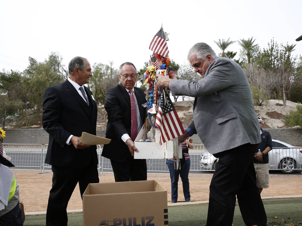 Clark County Commissioners, Jim Gibson, center, and Steve Sisolak, right, help removing crosses from the Route 91 Harvest memorial as Greg Zanis, who created the 58 crosses memorializing those who ...