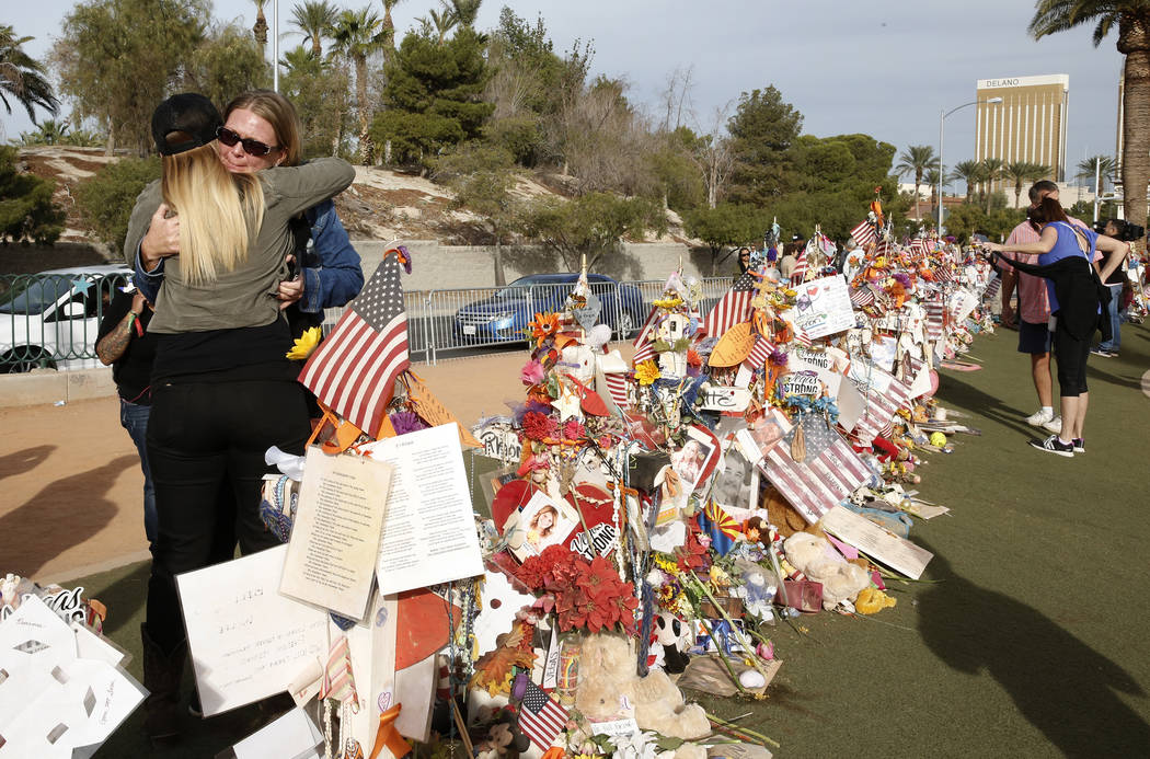Las Vegas shooting survivors Kristy-Marie Hoff, left, and Shawna Bartlett hug each other as they visit a memorial for Route 91 Harvest shooting victims at the Welcome to Fabulous Las Vegas sign Su ...