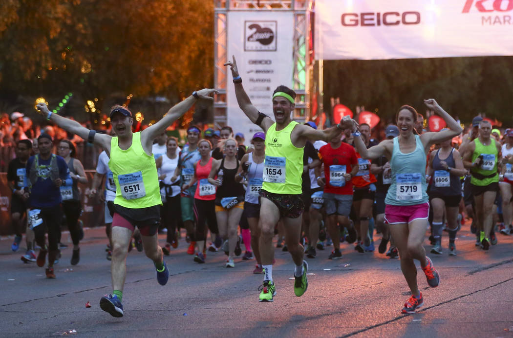 Participants, including, from left, Peter Smith, Scott Desbois, and Jen Desbois head out from the start line outside of the New York-New York at the beginning of the Rock 'n' Roll Marathon in Las  ...