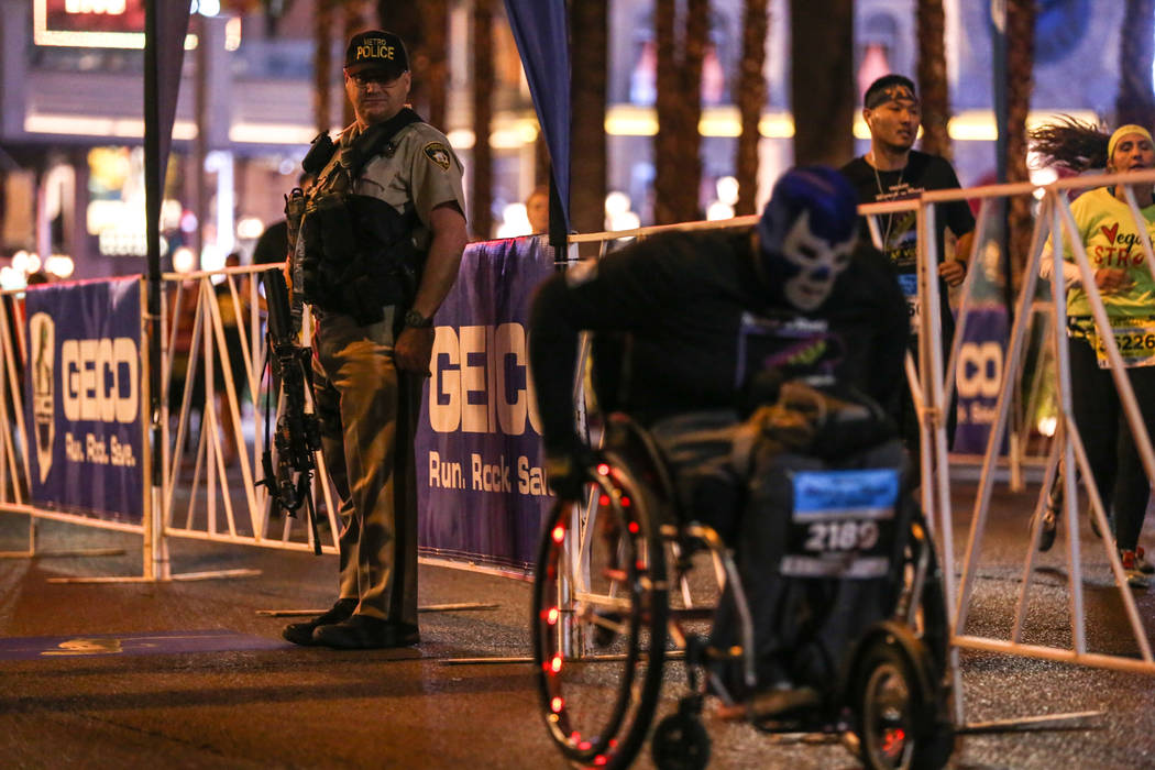 A police officer watches as a participant heads toward the finish line during the half marathon run of the Rock 'n' Roll Las Vegas Marathon along the Strip near The Mirage in Las Vegas, Sunday, No ...