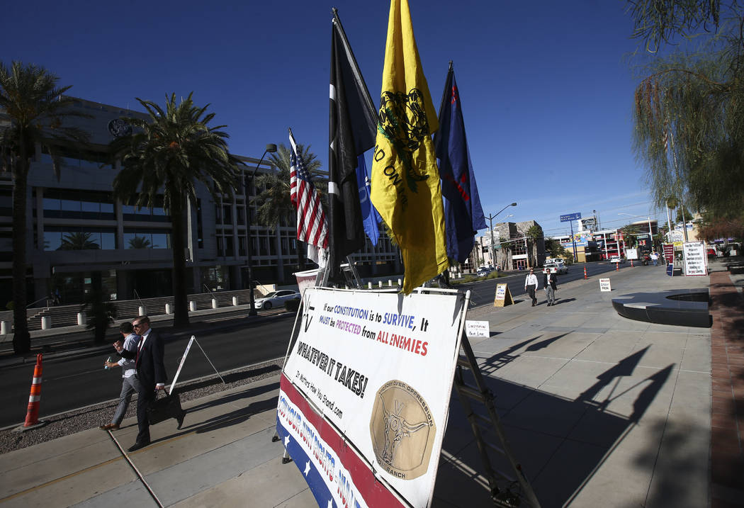 People walk past signs placed in support of the Bundy family and others outside the in Lloyd George U.S. Courthouse in downtown Las Vegas on Tuesday, Nov. 14, 2017. Opening statements were deliver ...
