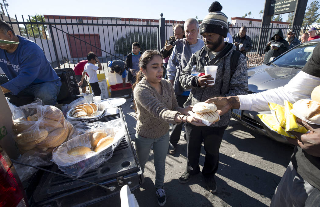 Homeless advocate Stephanie Bravo, center, hands out warm meals to a line of people on Foremaster Lane between Las Vegas Boulevard and Main Street in Las Vegas, Wednesday, Nov. 22, 2017. Richard B ...