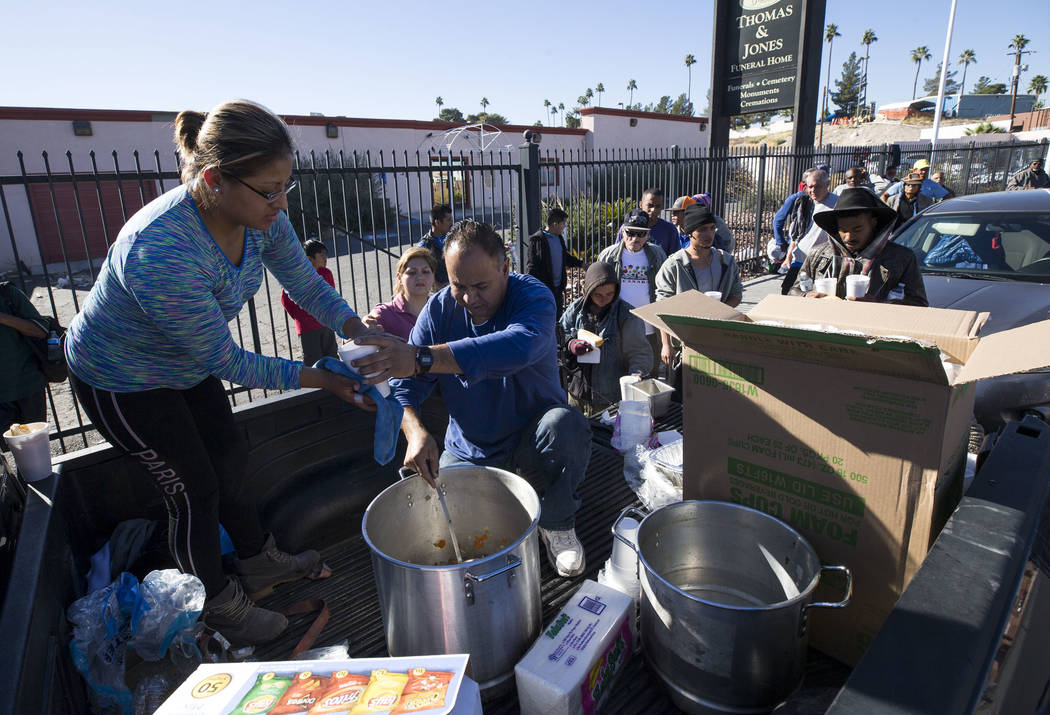 Homeless advocates Elizabeth Hernandez, left, and Matthew Romero hand out warm meals to a line of people on Foremaster Lane between Las Vegas Boulevard and Main Street in Las Vegas, Wednesday, Nov ...