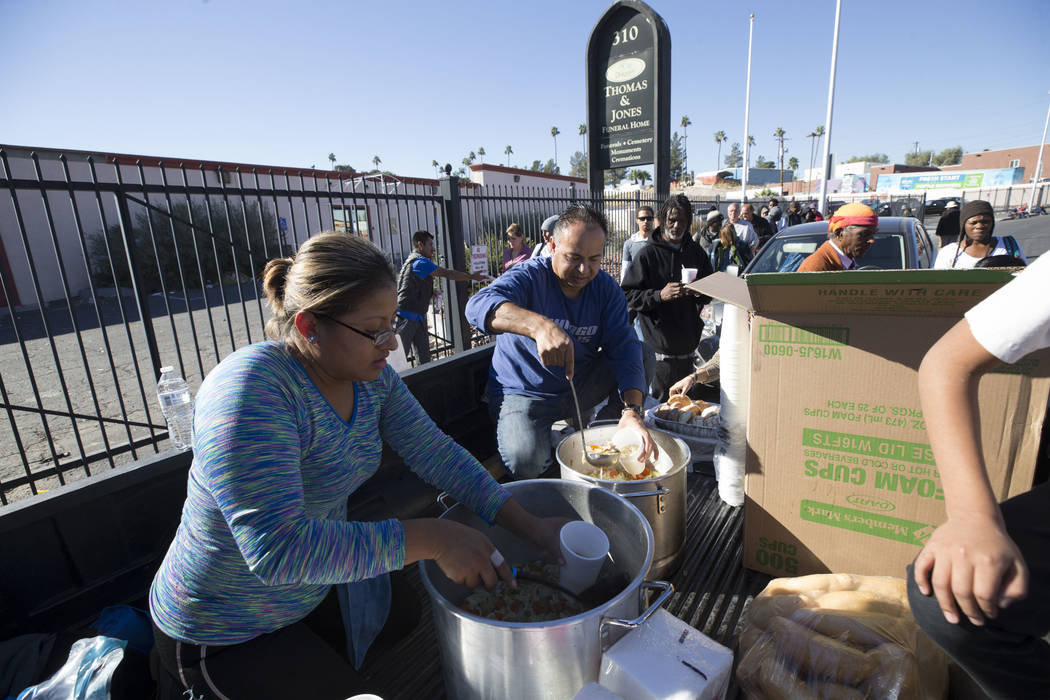 Homeless advocates Elizabeth Hernandez, left, and Matthew Romero hand out warm meals to a line of people on Foremaster Lane between Las Vegas Boulevard and Main Street in Las Vegas, Wednesday, Nov ...