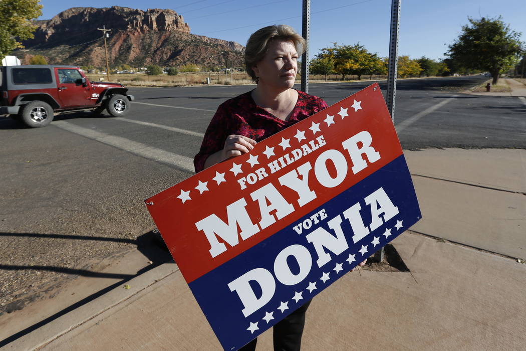 Donia Jessop holds her mayoral campaign sign outside her store in Colorado City, Ariz., last month.  (AP Photo/Rick Bowmer, File)
