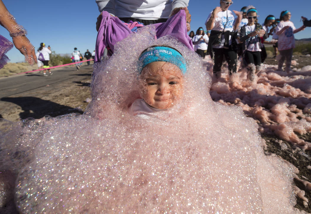 Eighteen-month-old Aniyah Vinson and her father Bruce emerge from the foam as they take part in the Bubble Run 5K event at Sam Boyd Stadium in Las Vegas, Saturday, Nov. 18, 2017. Richard Brian Las ...