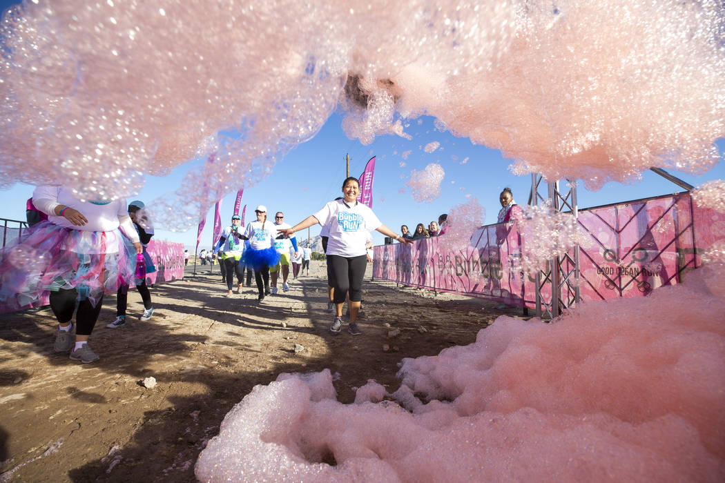 Participants run through foam sprayers during the Bubble Run 5K event at Sam Boyd Stadium in Las Vegas, Saturday, Nov. 18, 2017. Richard Brian Las Vegas Review-Journal @vegasphotograph