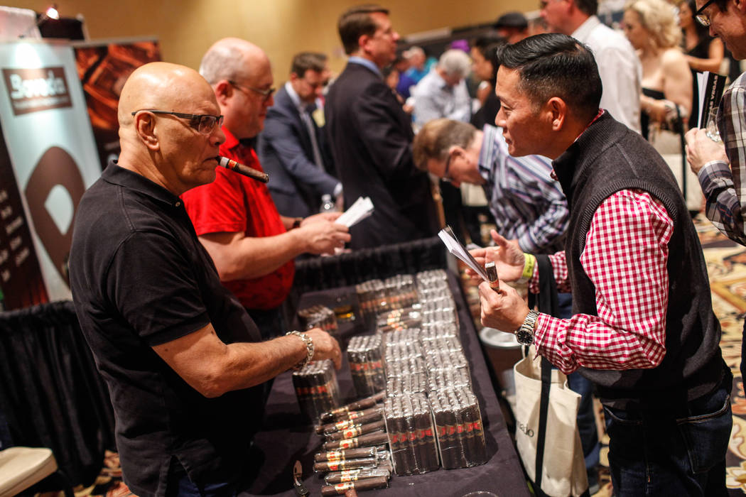 Ernesto Perez Carrillo, 66, owner of EP Carrillo, left, hands out cigars to patrons during the Cigar Aficionado's Big Smoke Las Vegas weekend event at The Mirage in Las Vegas, Saturday, Nov. 18, 2 ...