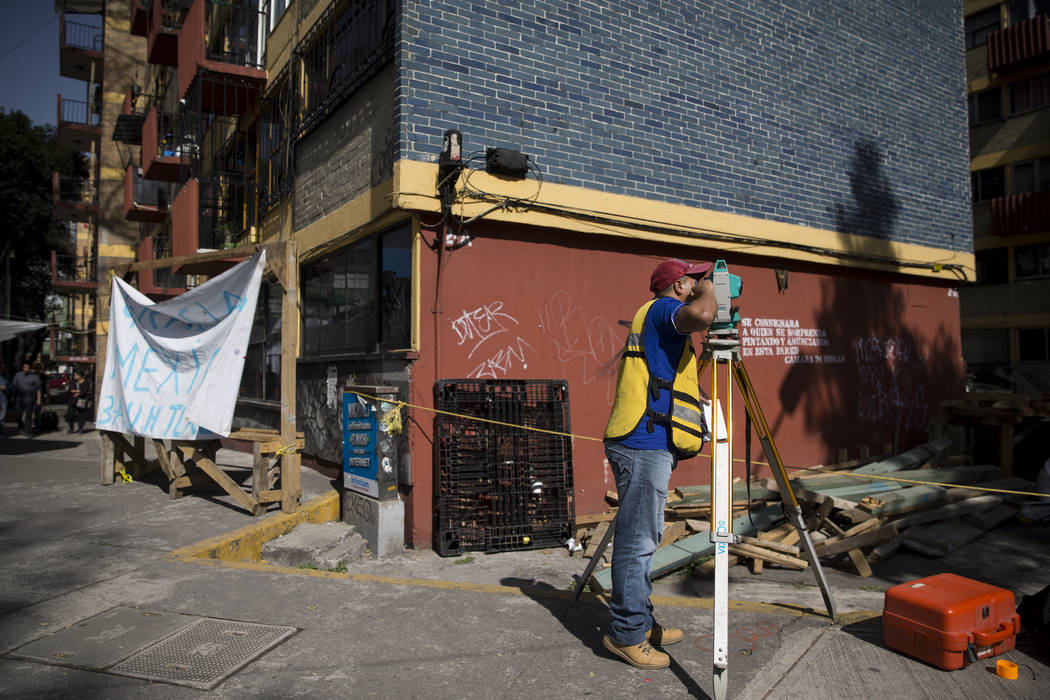 A worker outside of the uninhabited apartment complex, Unidad Habitacional de Tlalpan, which suffered structural damage during the Sept. 19 earthquake, takes measurements from the sidewalk in Mexi ...