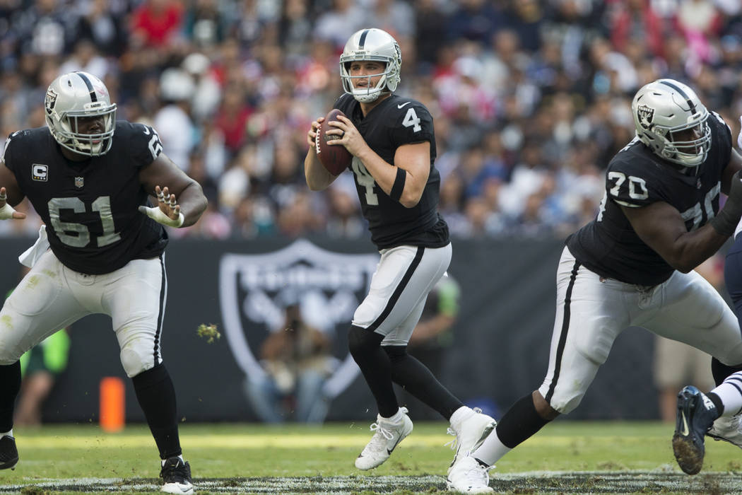 Oakland Raiders quarterback Derek Carr (4) looks for an open pass against the New England Patriots in the NFL football game at Estadio Azteca in Mexico City, Sunday, Nov. 19, 2017. Erik Verduzco L ...