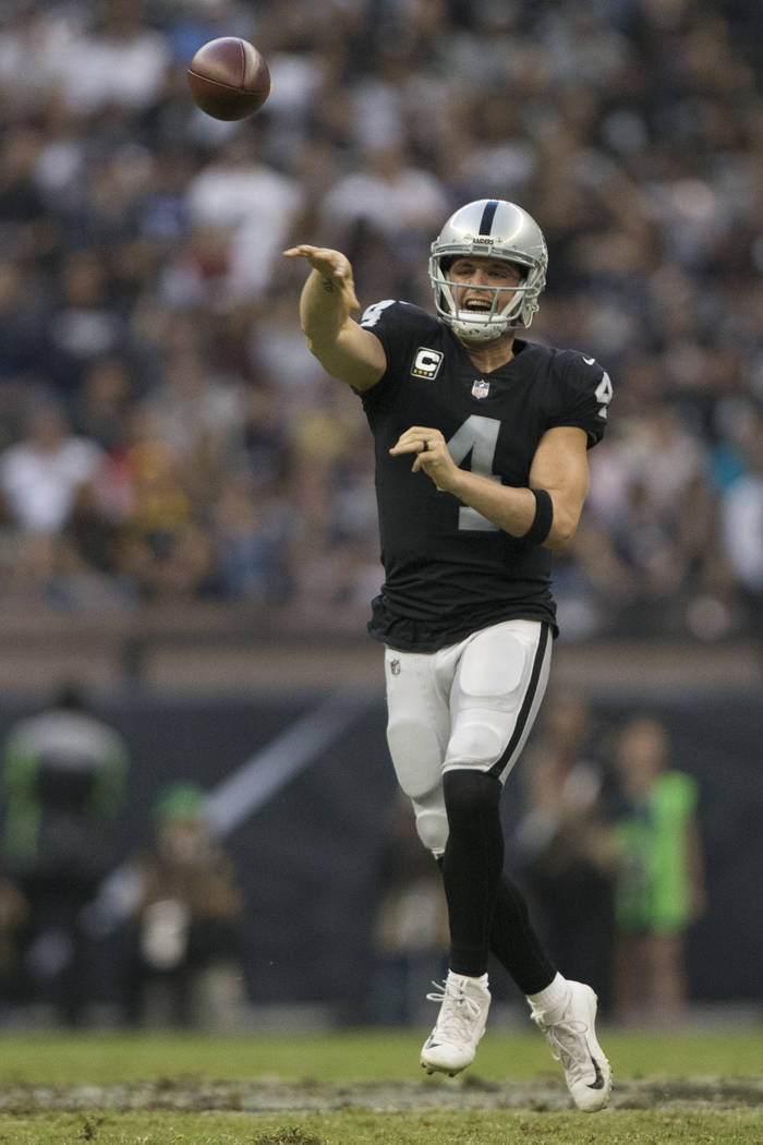 Oakland Raiders quarterback Derek Carr (4) throws the ball against the New England Patriots in the NFL football game at Estadio Azteca in Mexico City, Sunday, Nov. 19, 2017. New England Patriots w ...