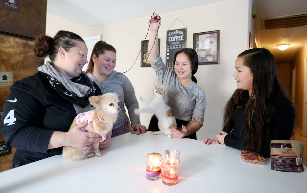 Elena Saccapilltio, left, holds her dog while her daughters Jazmen Segars, 19, left, Kalena Segars, 15, center, and Rozlyn Segars, 13, play with their kitten in their home in Las Vegas on Tuesday, ...
