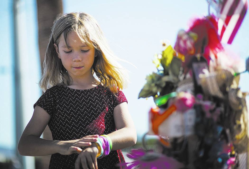 Seven-year-old Brooke Patterson of Lomita, Calif. visits a makeshift memorial for her mother, Lisa Patterson, who was one of 58 people who died in the Oct. 1 shooting at a music festival, near the ...