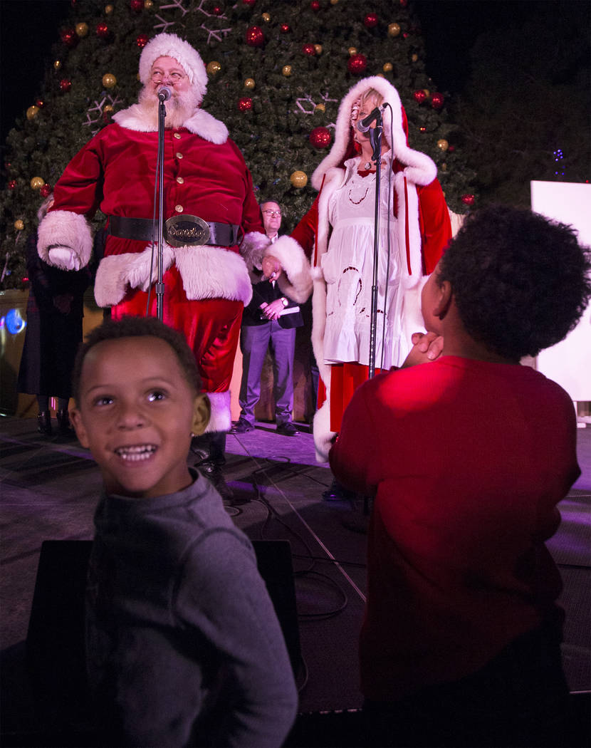 Santa and Mrs. Claus sing a song to the crowd as Madden Flaathen, left/front, smiles with excitement at Opportunity Village's Magical Forest on Friday, Nov. 24, 2017, in Las Vegas. Benjamin Hager  ...