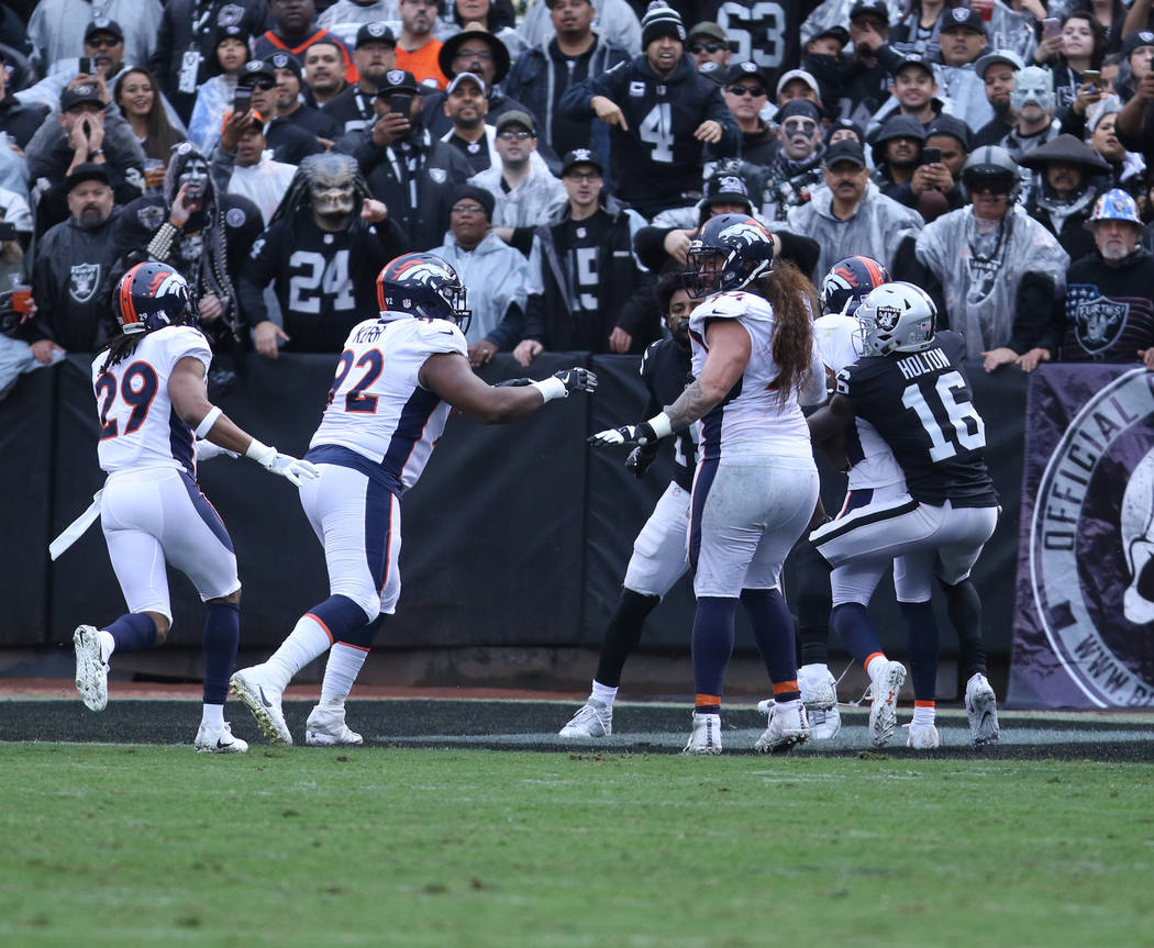 Denver Broncos players rush in as Oakland Raiders wide receiver Johnny Holton (16) holds Denver Broncos cornerback Aqib Talib (21) back from Oakland Raiders wide receiver Michael Crabtree (15) dur ...