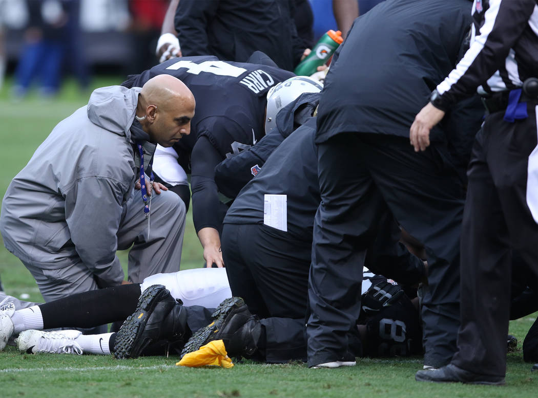 Oakland Raiders quarterback Derek Carr (4) comes over to check on his concussed wide receiver, Amari Cooper (89), as trainers tend to him during the first half of a NFL game against the Denver Bro ...
