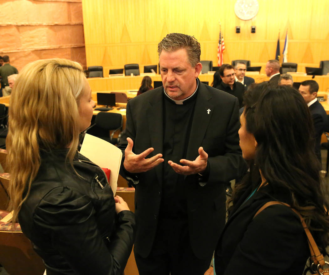 Deacon Thomas Roberts, speaks to survivors of the Oct. 1 Las Vegas shooting, Laura Puglia, left, and Lillian Aguirre after the Las Vegas Victims Fund committee's town hall meeting Tuesday, Nov. 28 ...