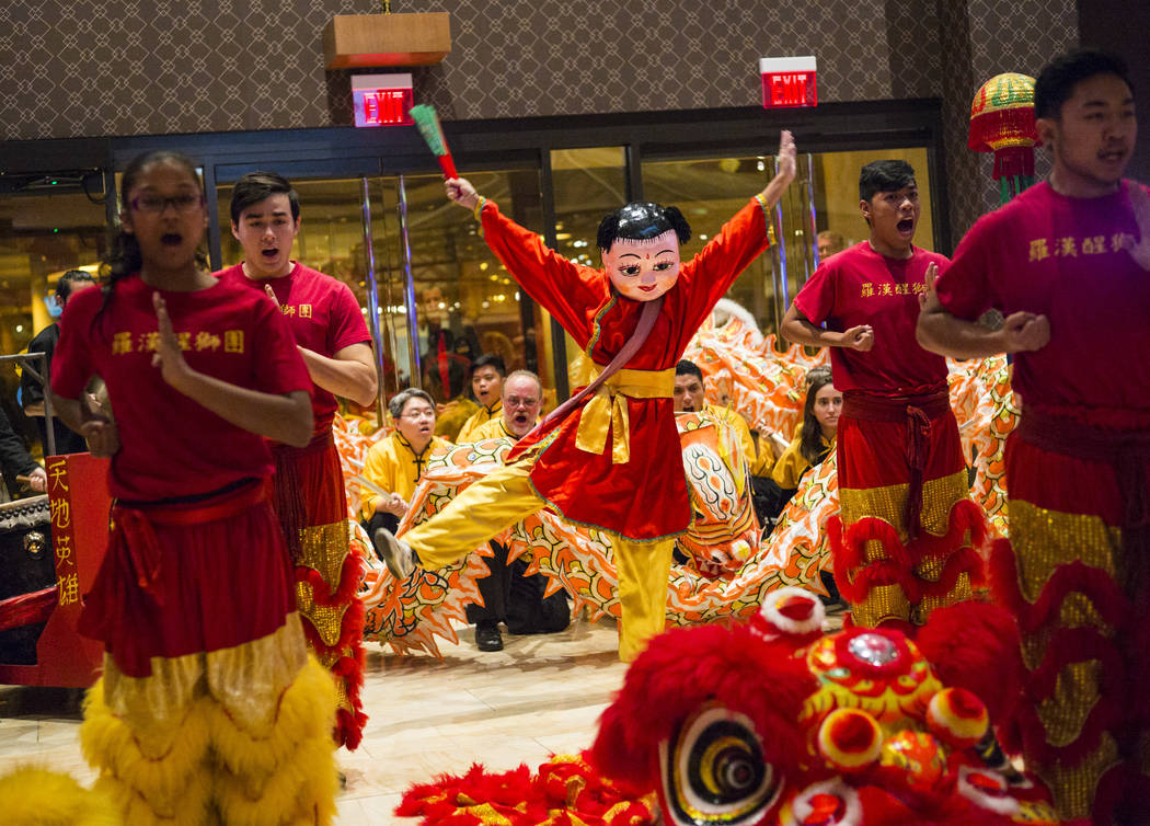 Members of the Lohan School of Shaolin, including Ronalli Enriquez dressed as Buddha, center, entertain the crowd with a traditional lion and dragon dance during the 1-year anniversary of the Luck ...