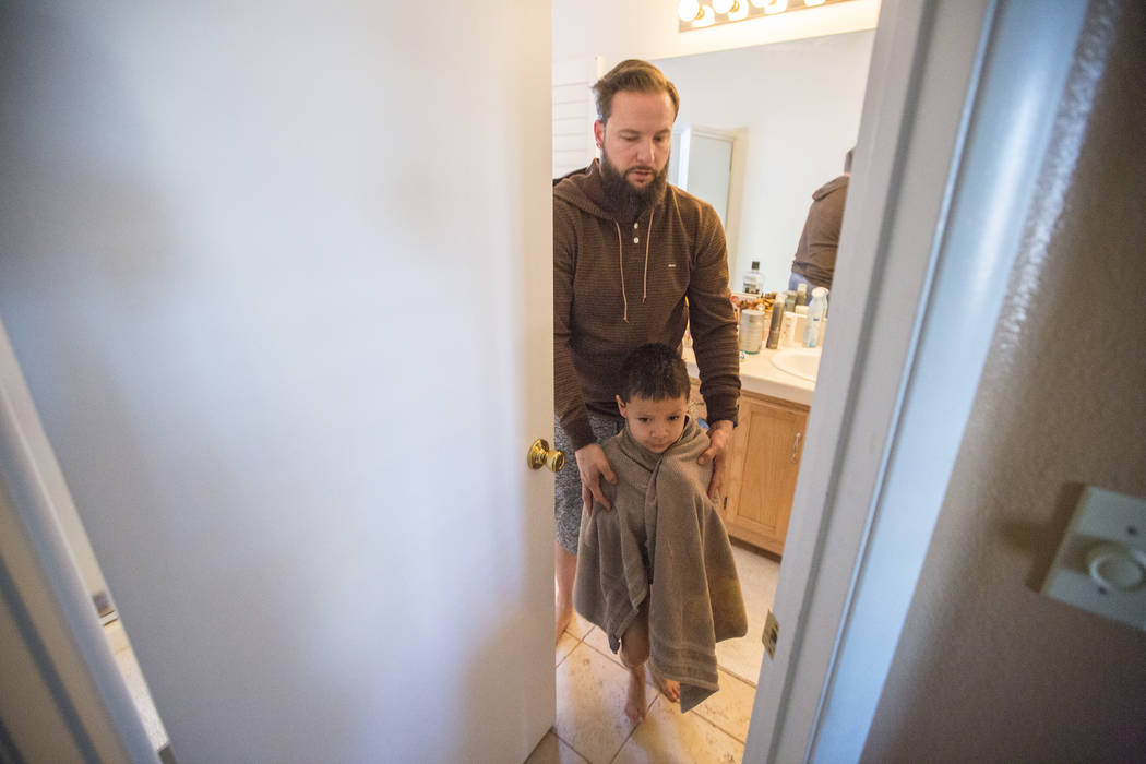 Maximus Calderon, 6, gets ready for school with the help of his dad William King in their home Friday morning, Dec. 8, 2017 while they get ready for school, in Las Vegas. Elizabeth Brumley Las Veg ...